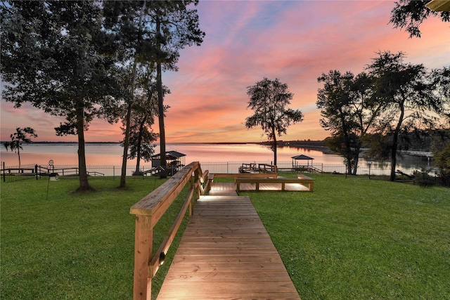 dock area featuring a yard, fence, and a water view