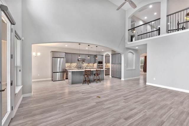 unfurnished living room with light wood-style flooring, recessed lighting, arched walkways, baseboards, and ceiling fan