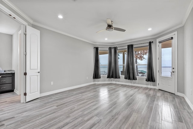 empty room with ceiling fan, baseboards, light wood finished floors, and ornamental molding