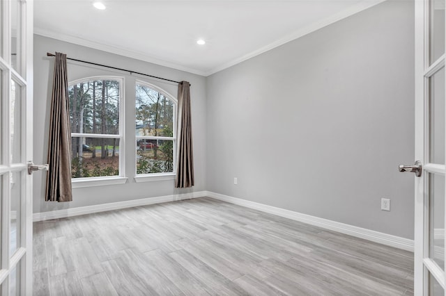 empty room featuring light wood-style flooring, french doors, baseboards, and ornamental molding