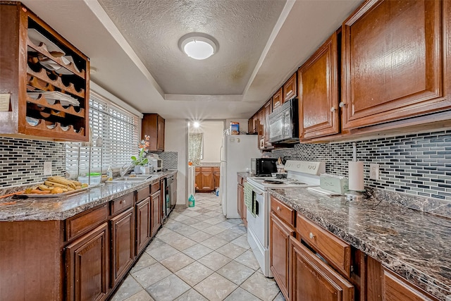 kitchen with backsplash, dark stone counters, black appliances, a raised ceiling, and a textured ceiling