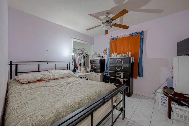 bedroom featuring a textured ceiling, a closet, ceiling fan, and light tile patterned flooring