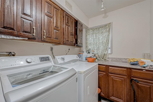 laundry room featuring washer and clothes dryer and cabinets