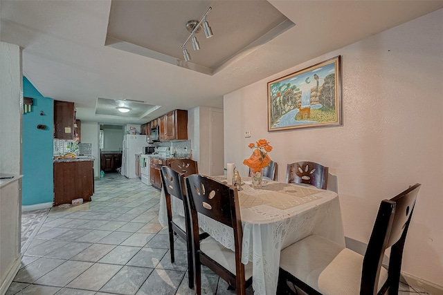 tiled dining area with a tray ceiling