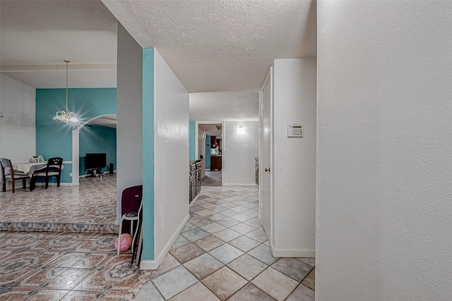 hallway with an inviting chandelier, light tile patterned flooring, and a textured ceiling