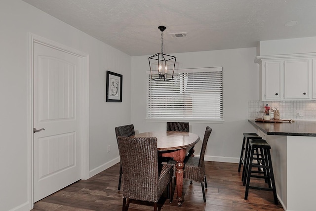 dining area featuring dark hardwood / wood-style flooring, a textured ceiling, and a notable chandelier