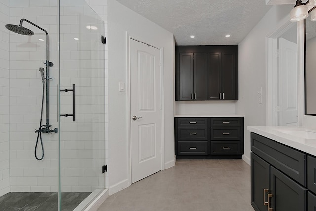 bathroom with vanity, tile patterned floors, a textured ceiling, and a shower with shower door