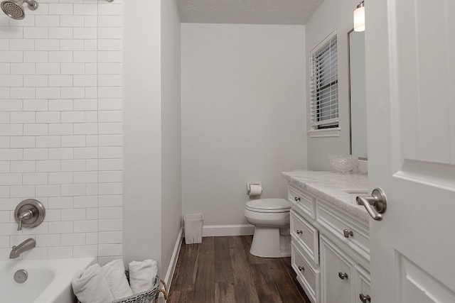 full bathroom with toilet, tiled shower / bath, a textured ceiling, vanity, and hardwood / wood-style flooring