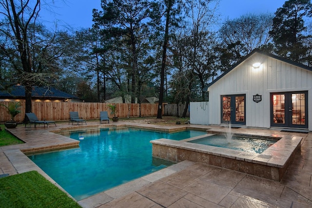 pool at dusk featuring a patio, an outbuilding, and french doors