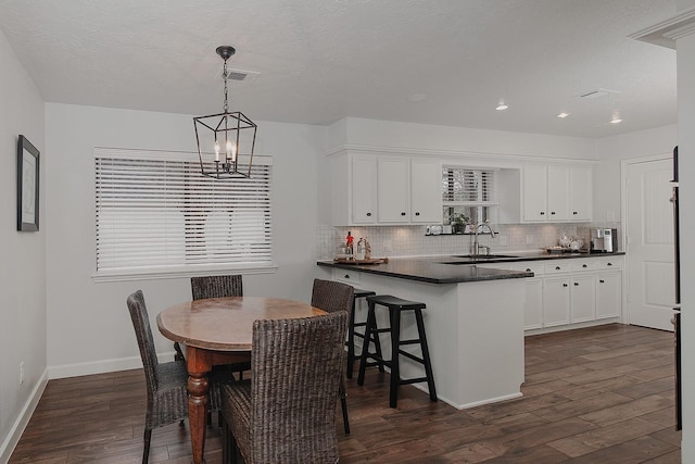 dining room featuring dark hardwood / wood-style flooring, sink, a notable chandelier, and a textured ceiling