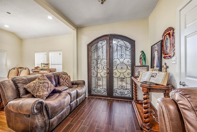 foyer with dark hardwood / wood-style flooring, lofted ceiling, french doors, and a textured ceiling