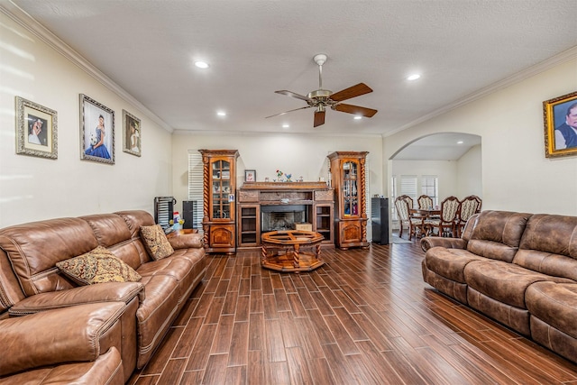 living room with ornamental molding, dark wood-type flooring, a textured ceiling, and ceiling fan