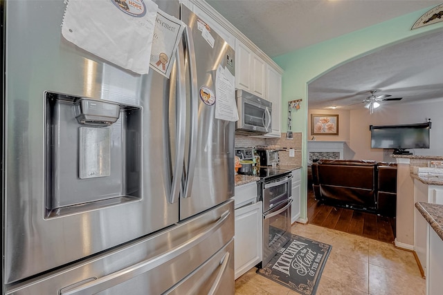 kitchen with ceiling fan, appliances with stainless steel finishes, light stone counters, tasteful backsplash, and white cabinets