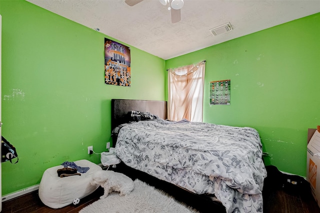 bedroom featuring ceiling fan, wood-type flooring, and a textured ceiling