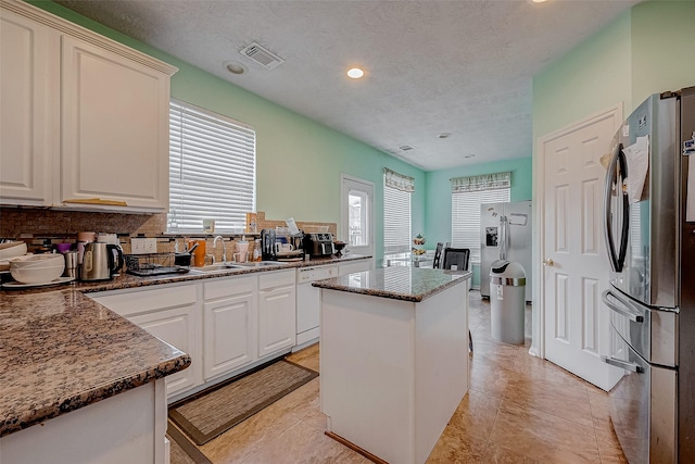 kitchen with stainless steel fridge, sink, a kitchen island, and white dishwasher