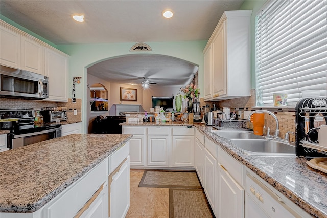 kitchen featuring appliances with stainless steel finishes, sink, white cabinets, light stone counters, and ceiling fan