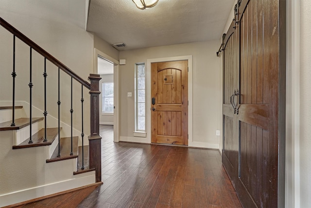 entryway featuring a barn door, dark hardwood / wood-style floors, and a textured ceiling