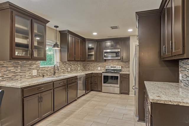 kitchen featuring pendant lighting, tasteful backsplash, sink, dark brown cabinetry, and stainless steel appliances