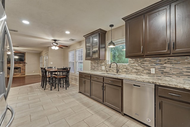 kitchen featuring dark brown cabinetry, sink, a fireplace, and appliances with stainless steel finishes