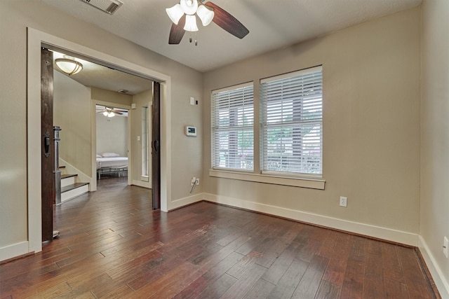 spare room with dark wood-type flooring and ceiling fan