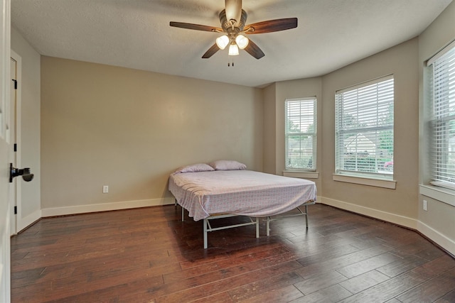 bedroom featuring dark wood-type flooring, ceiling fan, and a textured ceiling