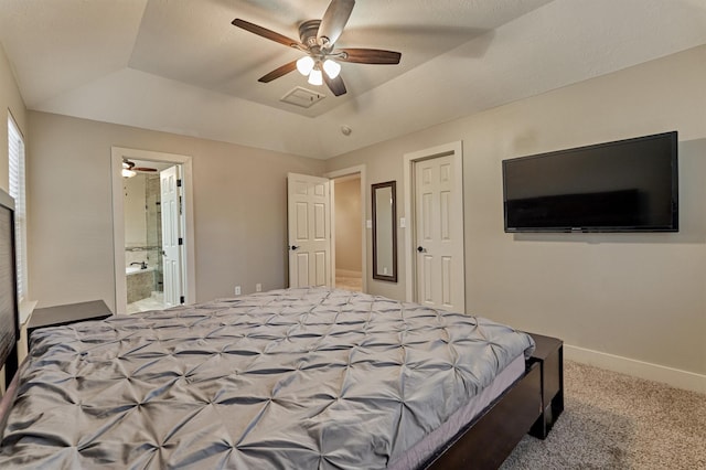 bedroom with ceiling fan, carpet flooring, a tray ceiling, and ensuite bath