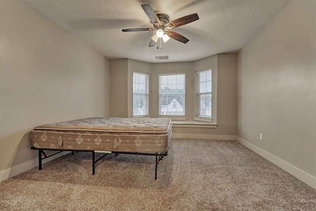 bedroom with ceiling fan, carpet floors, and a textured ceiling