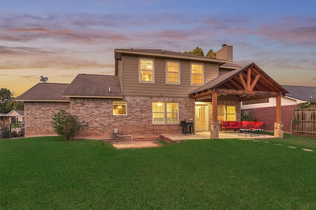 back house at dusk featuring a yard, an outdoor hangout area, and a patio area