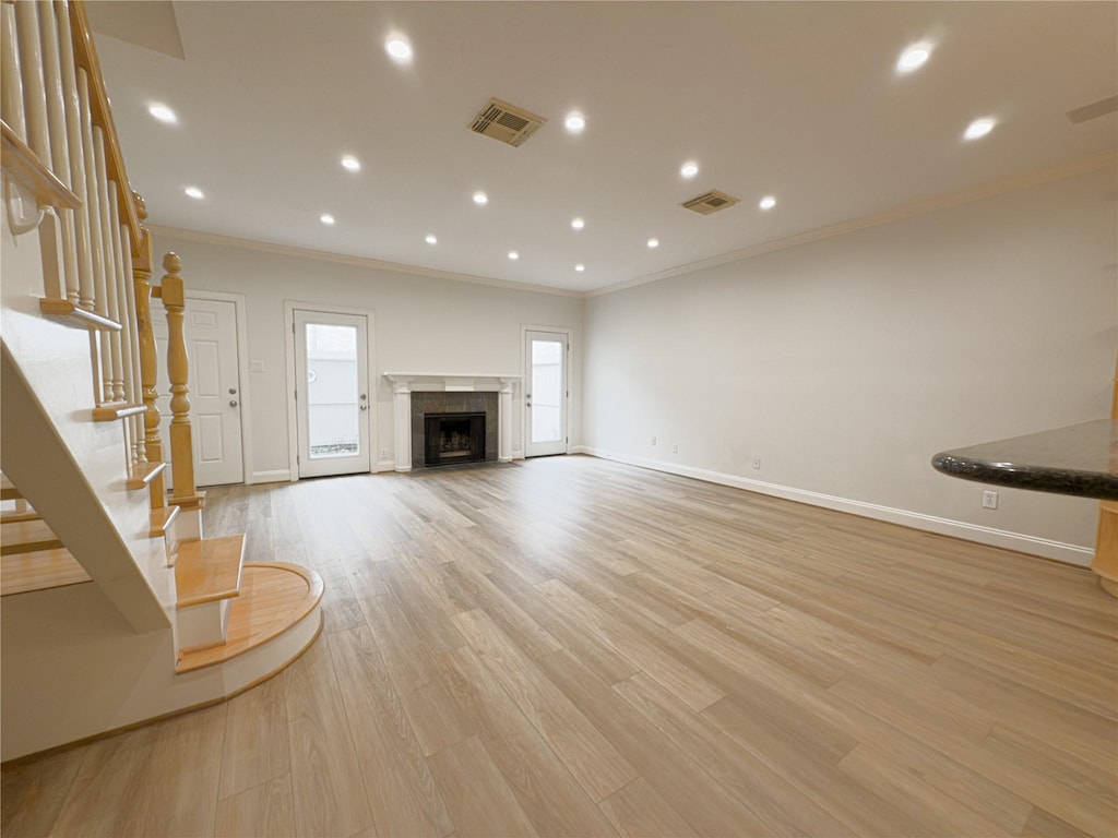 unfurnished living room with crown molding and light hardwood / wood-style floors