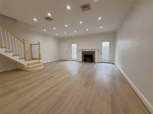 unfurnished living room featuring ornamental molding, a fireplace, and light hardwood / wood-style floors