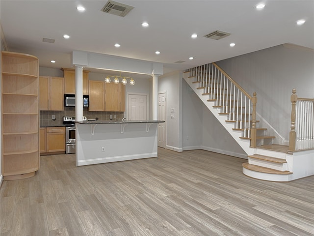 kitchen featuring light hardwood / wood-style flooring, stainless steel appliances, a kitchen breakfast bar, decorative columns, and light brown cabinets