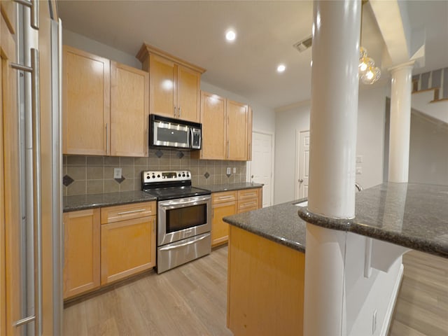 kitchen with decorative backsplash, stainless steel appliances, dark stone counters, and light wood-type flooring