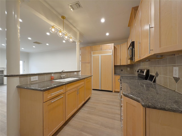 kitchen with sink, appliances with stainless steel finishes, light brown cabinetry, decorative light fixtures, and dark stone counters