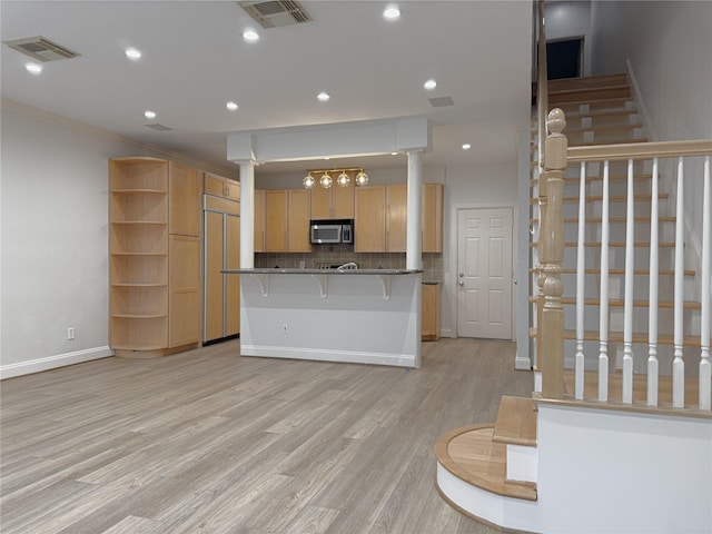 kitchen with a kitchen bar, light brown cabinets, kitchen peninsula, light hardwood / wood-style floors, and decorative backsplash