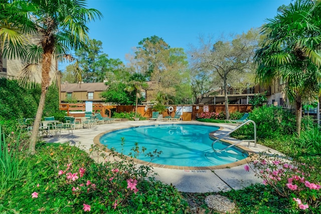 community pool with a patio and fence