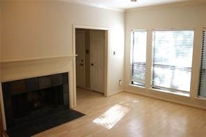 unfurnished living room featuring wood-type flooring and ornamental molding