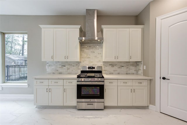 kitchen with white cabinetry, wall chimney exhaust hood, stainless steel gas range, and decorative backsplash