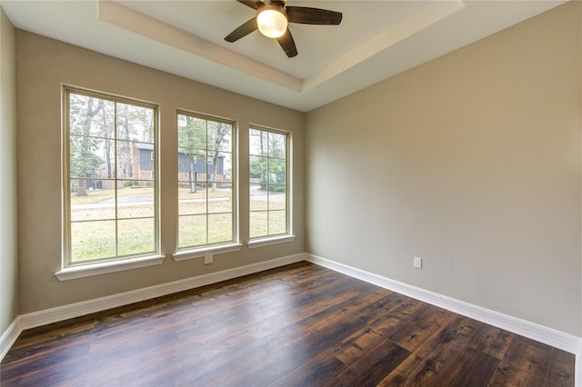 unfurnished room with ceiling fan, dark hardwood / wood-style flooring, and a raised ceiling