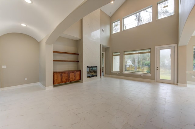 unfurnished living room with lofted ceiling and a high end fireplace