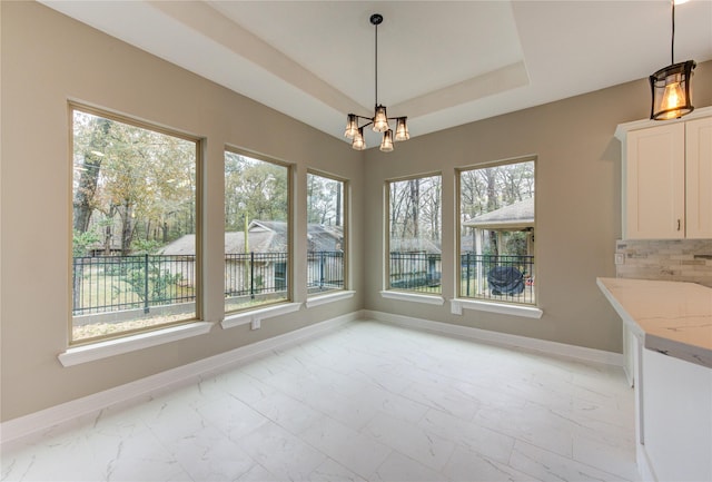 unfurnished dining area featuring a notable chandelier and a tray ceiling