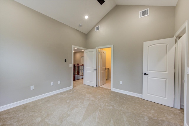 unfurnished bedroom with connected bathroom, light colored carpet, and high vaulted ceiling