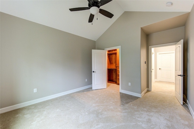 unfurnished bedroom featuring a walk in closet, high vaulted ceiling, light colored carpet, a closet, and ceiling fan