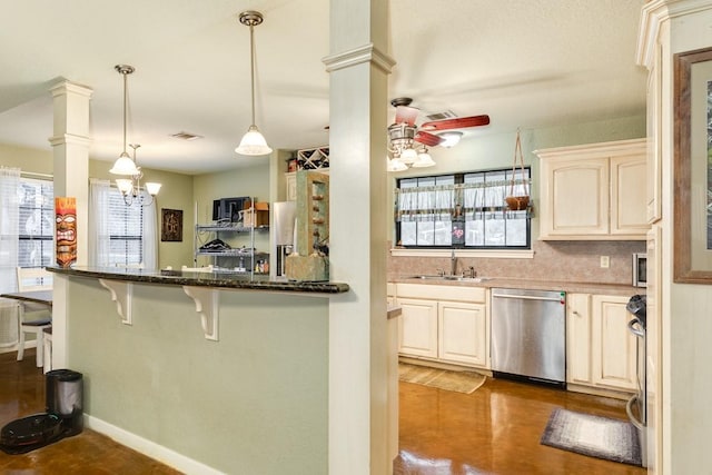 kitchen featuring stainless steel dishwasher, dark stone countertops, decorative light fixtures, and ornate columns