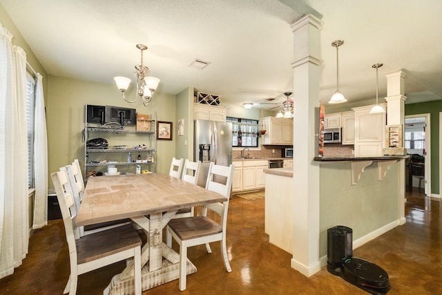 dining room featuring ornate columns, sink, and ceiling fan with notable chandelier