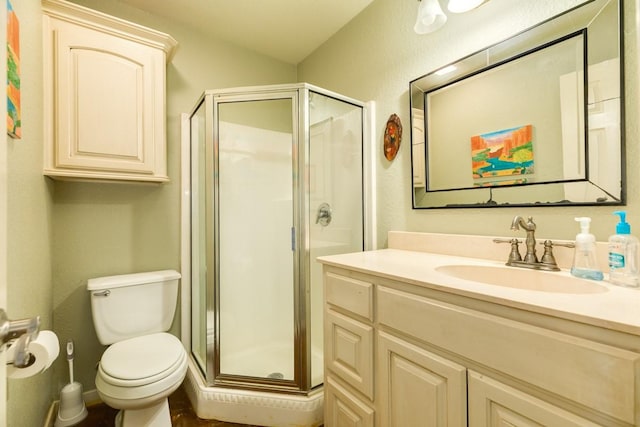 bathroom with a shower with door, vanity, and toilet