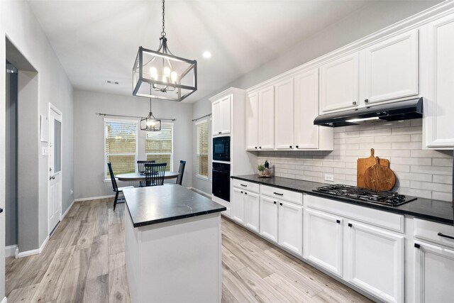 kitchen featuring white cabinetry, hanging light fixtures, black appliances, light hardwood / wood-style floors, and a kitchen island