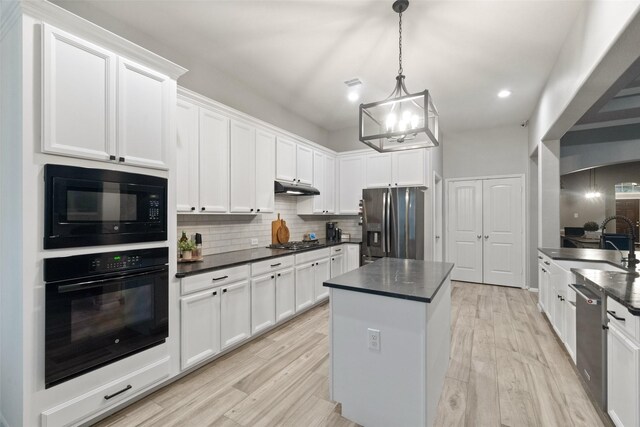 kitchen with a kitchen island, white cabinetry, backsplash, hanging light fixtures, and black appliances