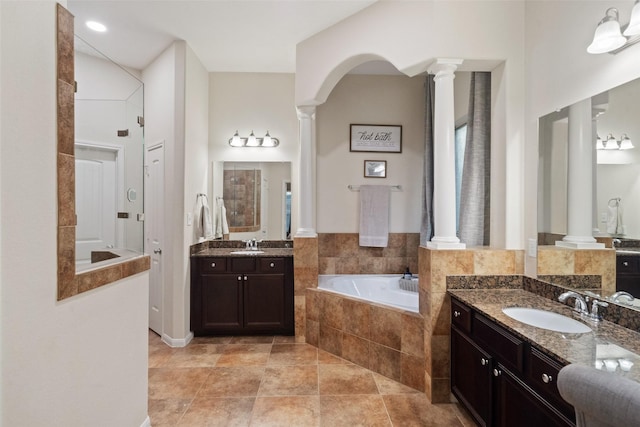 bathroom featuring a relaxing tiled tub, vanity, tile patterned flooring, and decorative columns