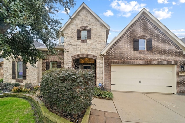 french country inspired facade with brick siding, stone siding, an attached garage, and concrete driveway