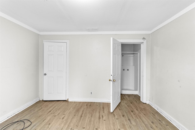 unfurnished bedroom with crown molding, a closet, and light wood-type flooring